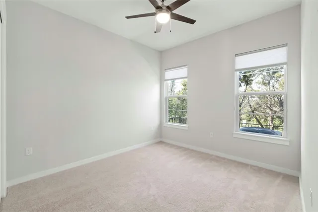 an empty room with a window and a ceiling fan