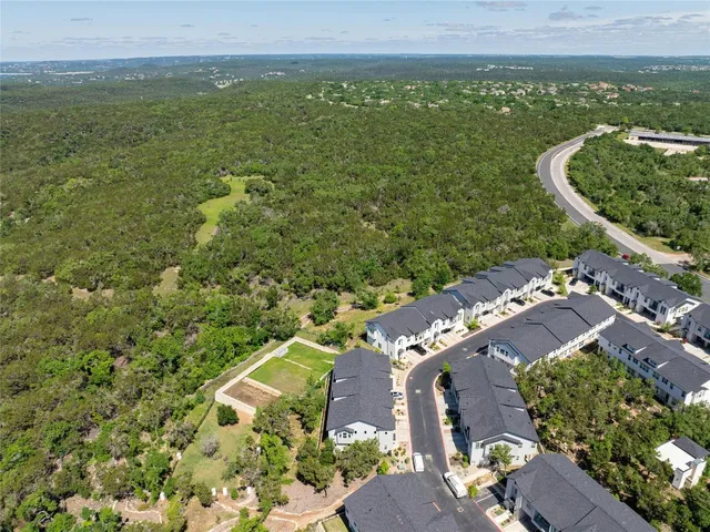 an aerial view of residential houses with outdoor space and trees