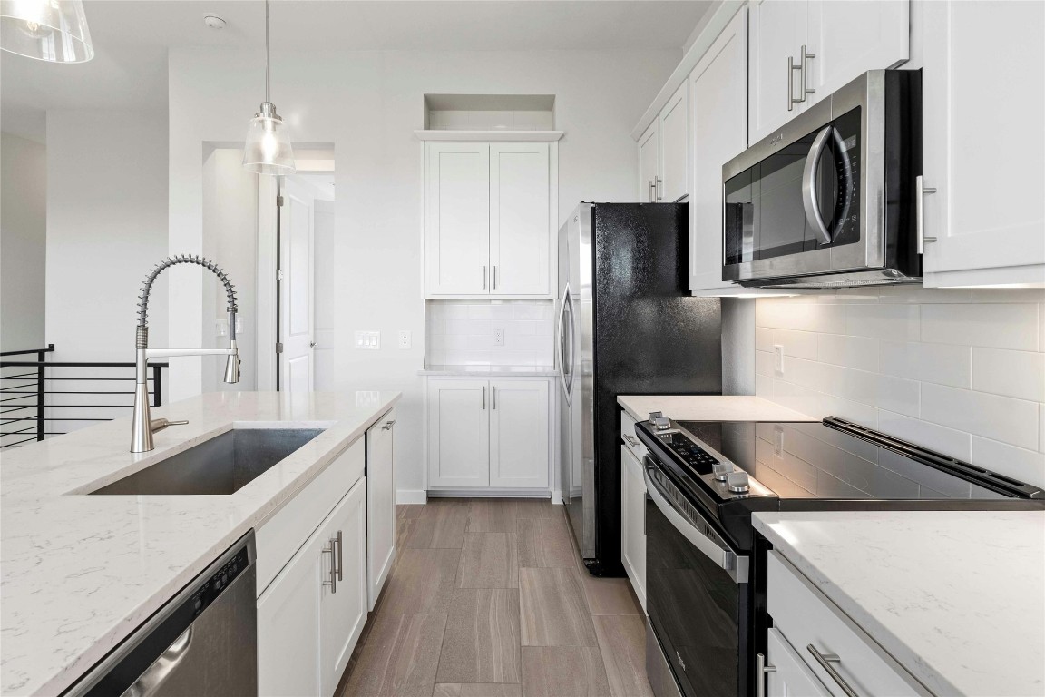 12001 Vista Parke Drive, Unit 702 Austin, TX 78726 - Photo 7 of 33 a kitchen with granite countertop a sink stainless steel appliances and cabinets