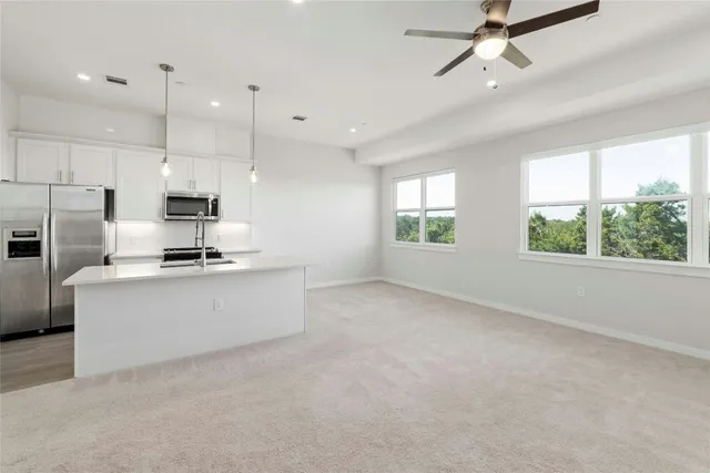 a large kitchen with stainless steel appliances kitchen island a large counter top a stove a refrigerator cabinets and living room view