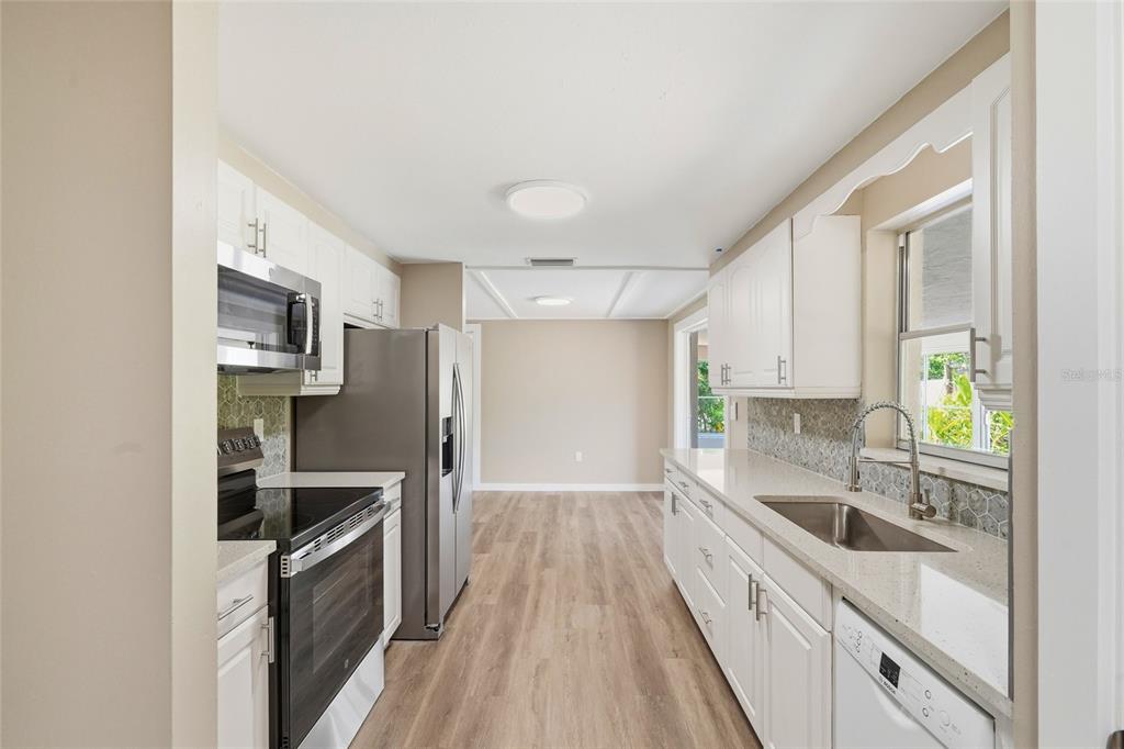 5984 Diana Road Venice, FL 34293 - Photo 14 of 36 a kitchen with granite countertop a sink wooden floor and stainless steel appliances