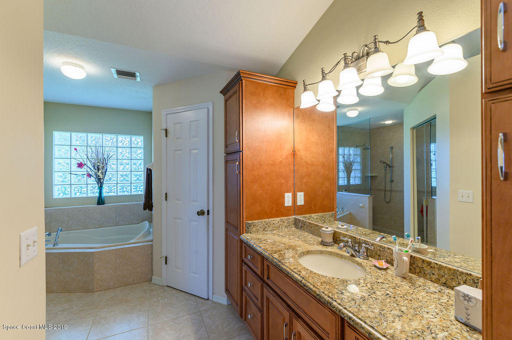 3525 Shady Run Road Melbourne, FL 32934 - Photo 25 of 32 a bathroom with a granite countertop sink a large mirror and a bathtub
