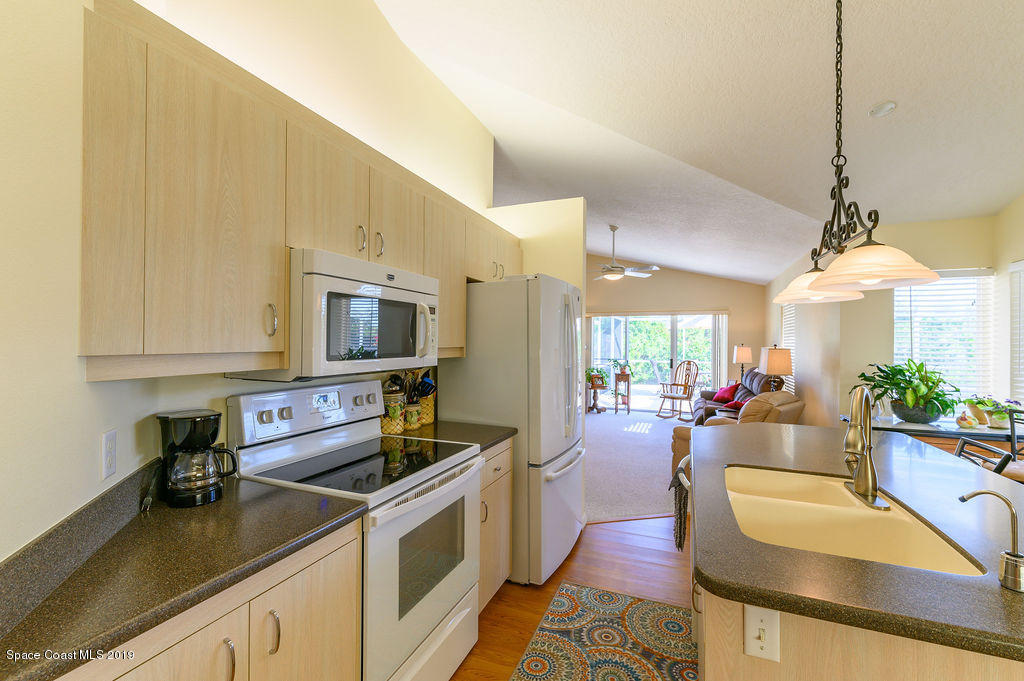 3525 Shady Run Road Melbourne, FL 32934 - Photo 28 of 32 a kitchen with a stove a sink a microwave a dining table and chairs