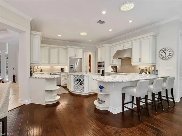 a kitchen with stainless steel appliances granite countertop a table chairs sink and cabinets