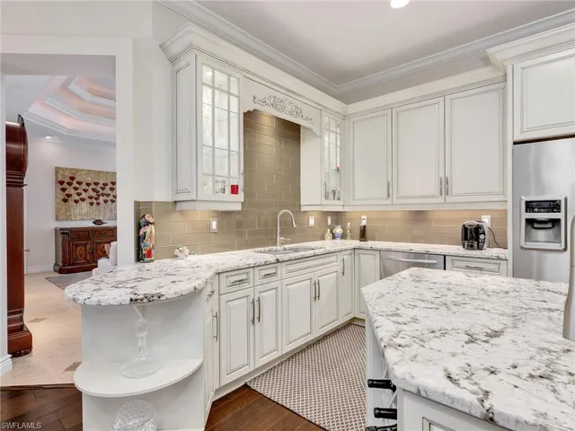 a kitchen with kitchen island granite countertop a sink stove and white cabinets