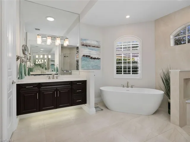 a spacious bathroom with a tub double sink mirror and window