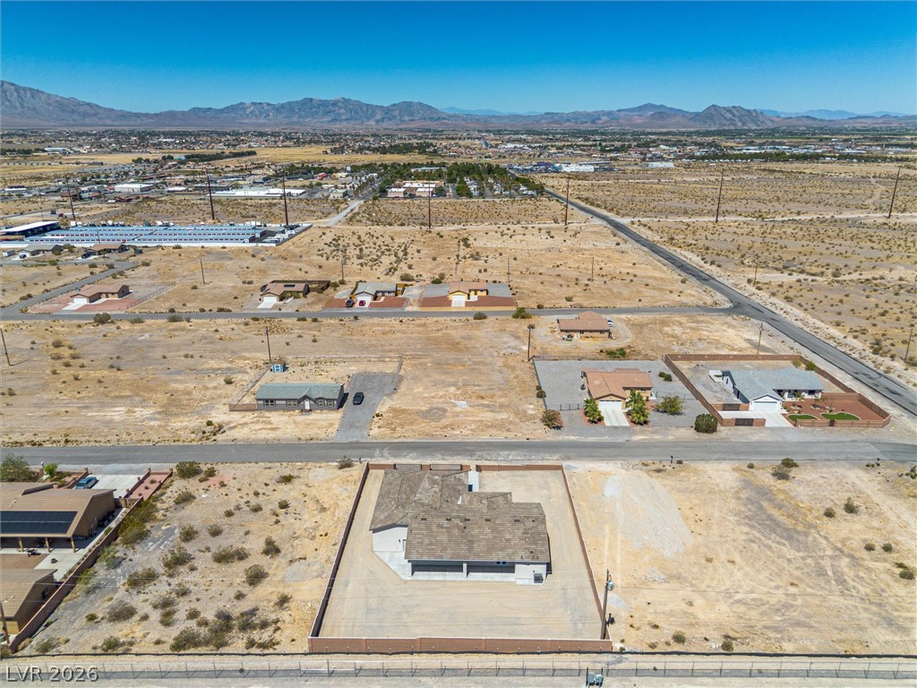 1061 Factory Road Pahrump, NV 89048 - Photo 40 of 41 An aerial perspective reveals a vast lot with a partially constructed structure, set against a distant mountain range.