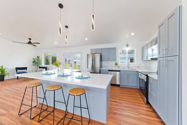 a kitchen with stainless steel appliances kitchen island granite countertop a refrigerator a stove a sink dishwasher and white cabinets with wooden floor