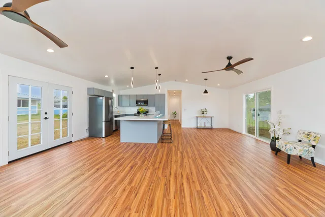 a large white kitchen with kitchen island a stove a refrigerator cabinets and wooden floor