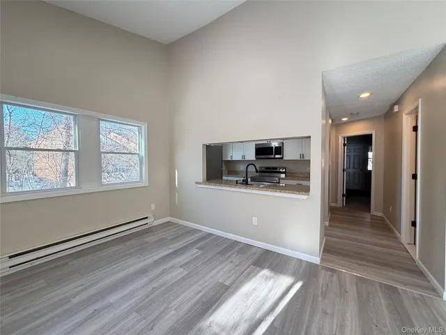 a view of kitchen and empty room with wooden floor