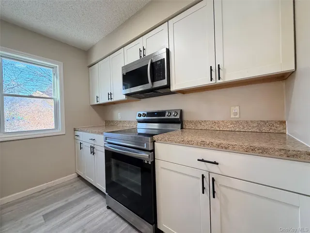 a kitchen with stainless steel appliances granite countertop white cabinets and a stove top oven