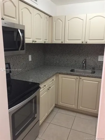 a kitchen with granite countertop white cabinets and stainless steel appliances