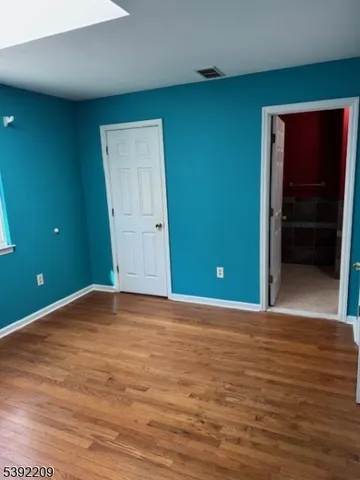 a view of an empty room with closet and a bathroom