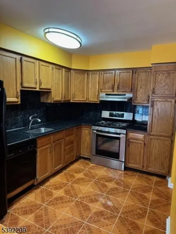 a kitchen with granite countertop a stove a sink and a microwave