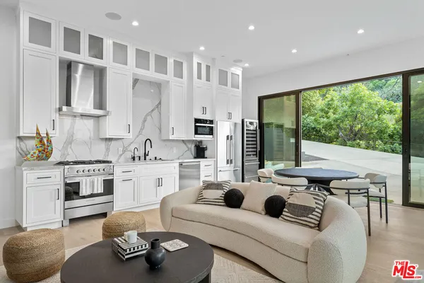 a kitchen with stainless steel appliances kitchen island granite countertop a dining table chairs microwave and sink