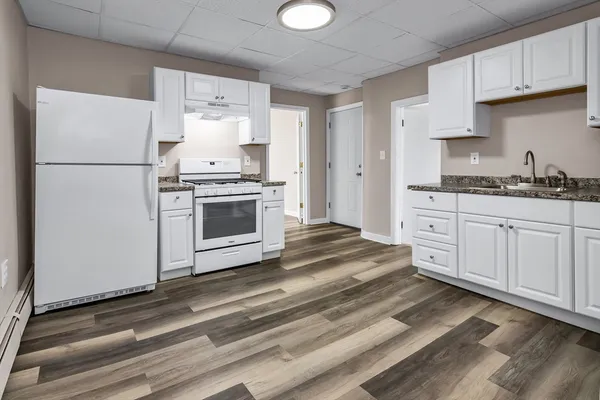 a kitchen with granite countertop white cabinets and white appliances