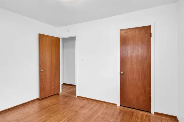 a view of an empty room with wooden floor and closet