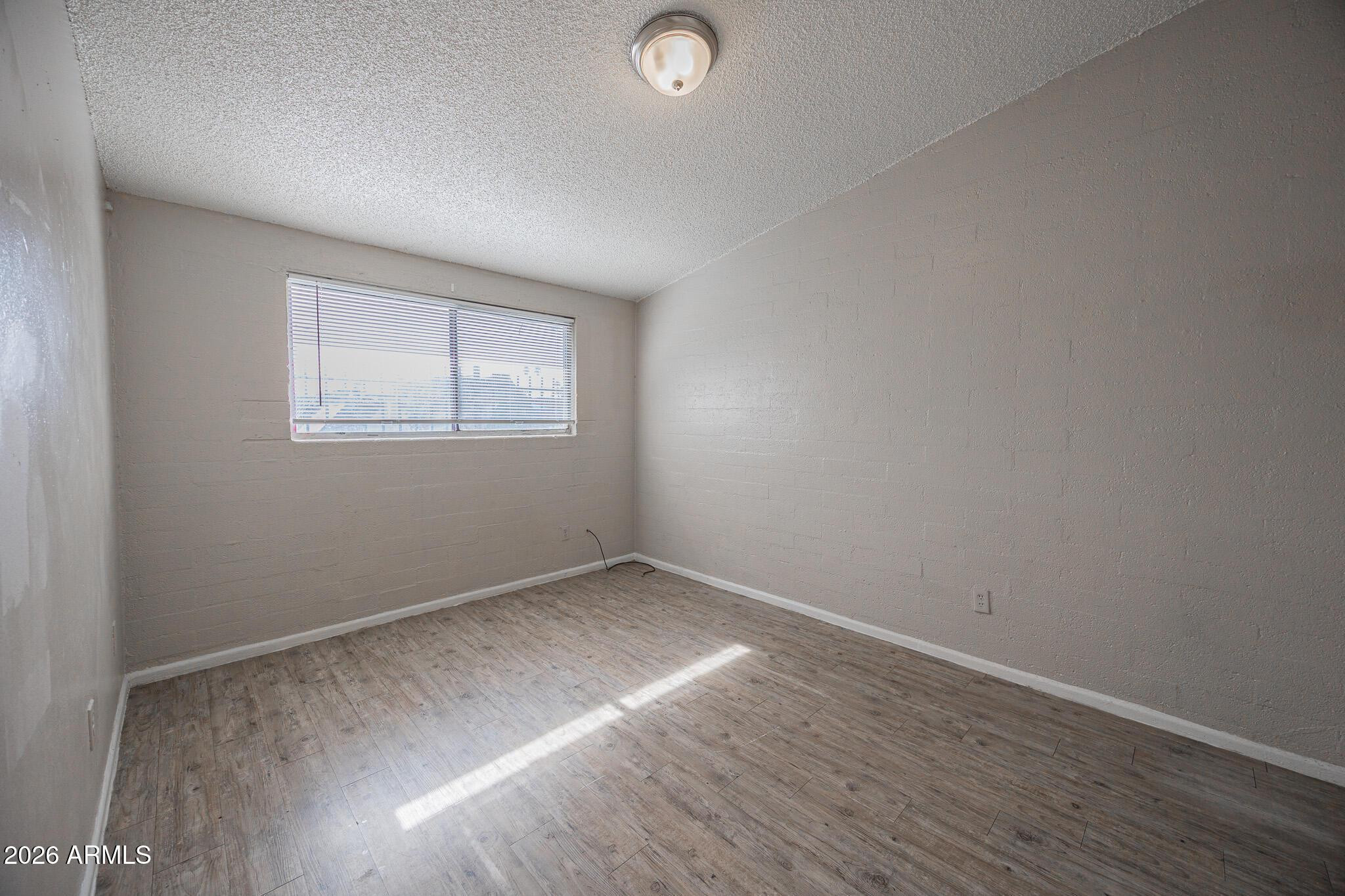 2123 West Devonshire Avenue, Unit 9 Phoenix, AZ 85015 - Photo 11 of 12 an empty room with wooden floor and windows