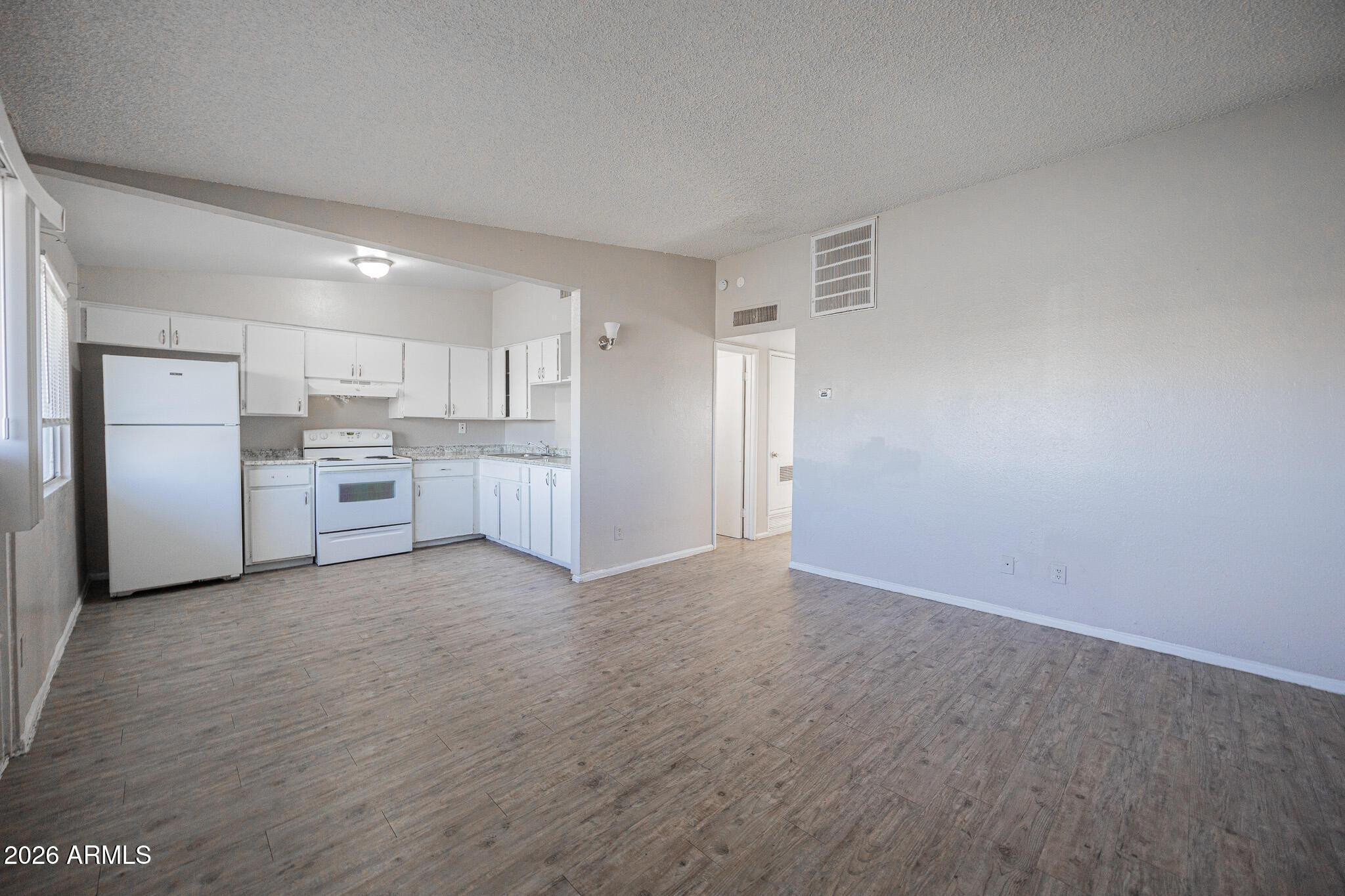 2123 West Devonshire Avenue, Unit 9 Phoenix, AZ 85015 - Photo 3 of 12 a view of a kitchen with a sink wooden cabinets and a refrigerator