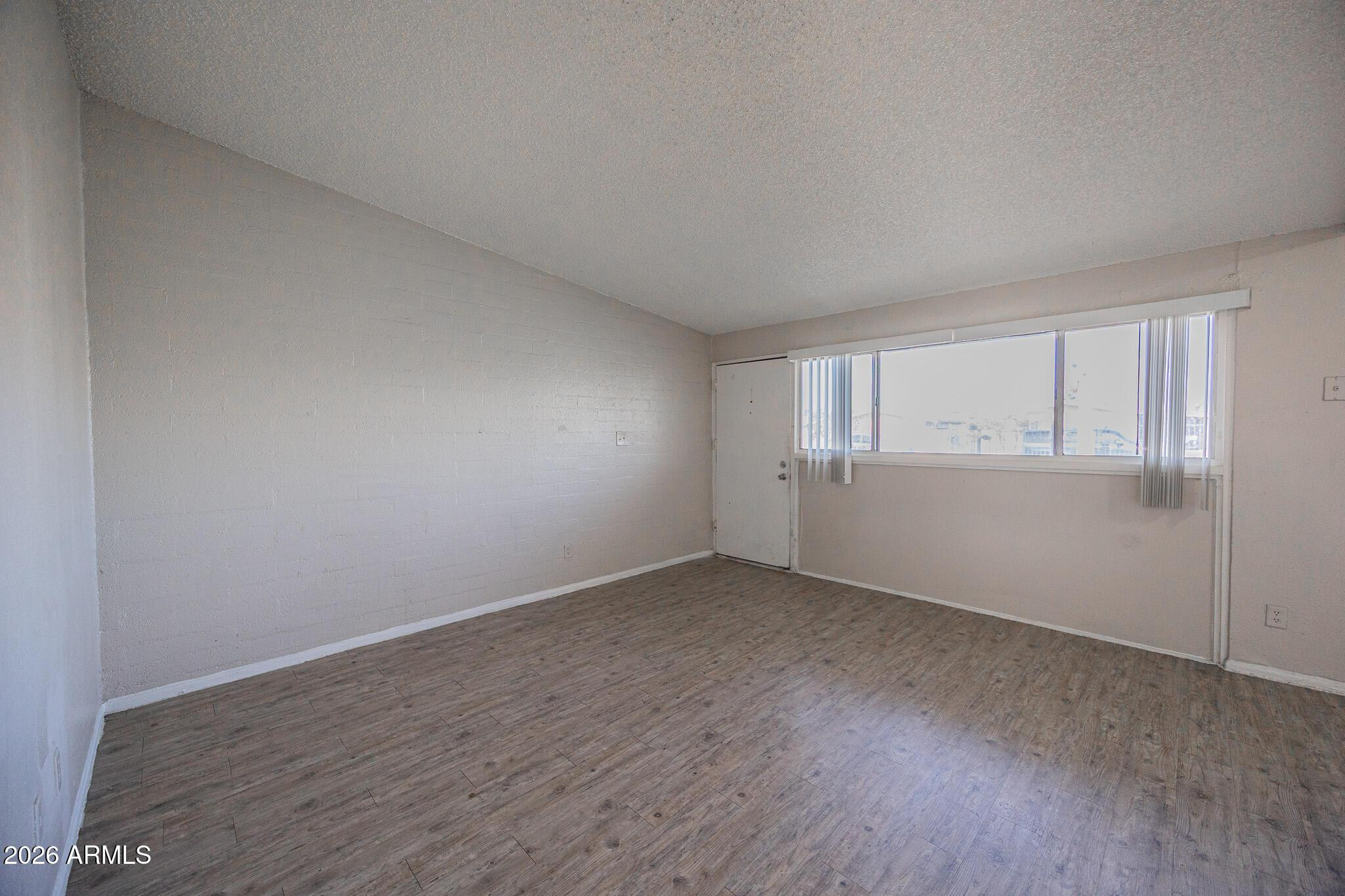 2123 West Devonshire Avenue, Unit 9 Phoenix, AZ 85015 - Photo 6 of 12 a view of an empty room with wooden floor and window