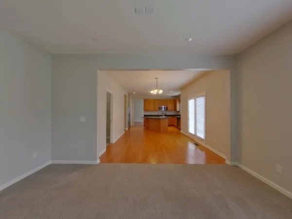 a kitchen with stainless steel appliances granite countertop a refrigerator a sink dishwasher a stove and a dining table with wooden floor