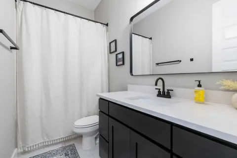 a bathroom with a granite countertop sink and a toilet