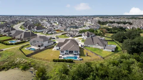 an aerial view of residential houses with outdoor space and trees
