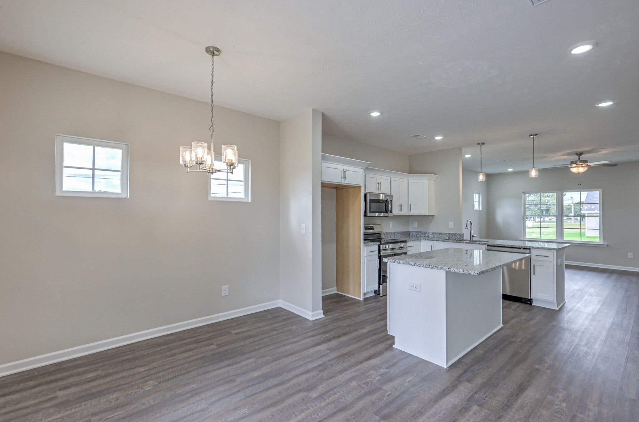 22 Bartow Street Decherd, TN 37324 - Photo 15 of 38 a open kitchen with stainless steel appliances granite countertop a refrigerator a stove top oven a sink dishwasher and white cabinets with wooden floor