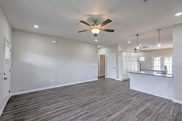 an empty room with wooden floor and a kitchen