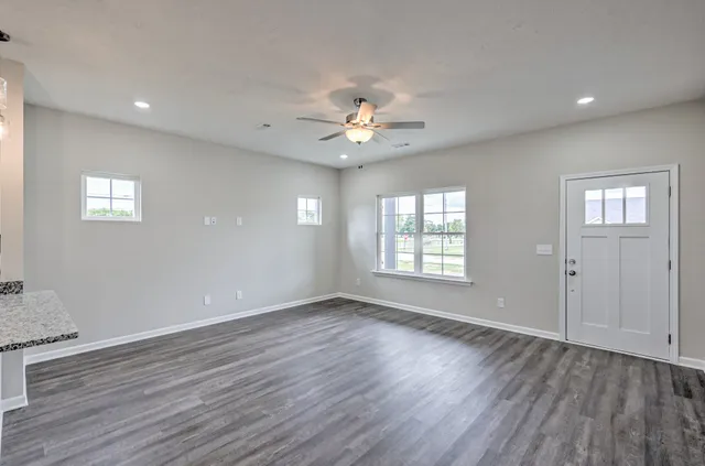 a view of an empty room with window and wooden floor