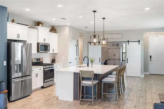 a kitchen with stainless steel appliances a stove a sink a microwave and refrigerator