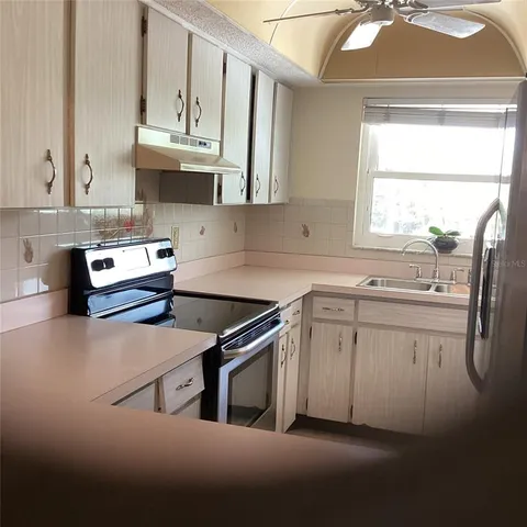 a kitchen with stainless steel appliances granite countertop a sink a stove and a granite counter tops with white cabinets