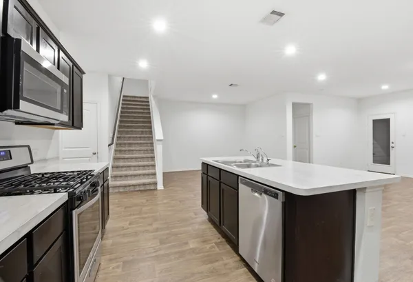 a kitchen with a sink and a stove top oven with wooden floor