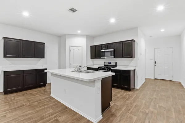 a kitchen with a sink a counter top space stainless steel appliances and cabinets