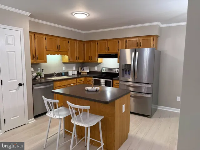 a kitchen with stainless steel appliances a sink a microwave a refrigerator and chairs