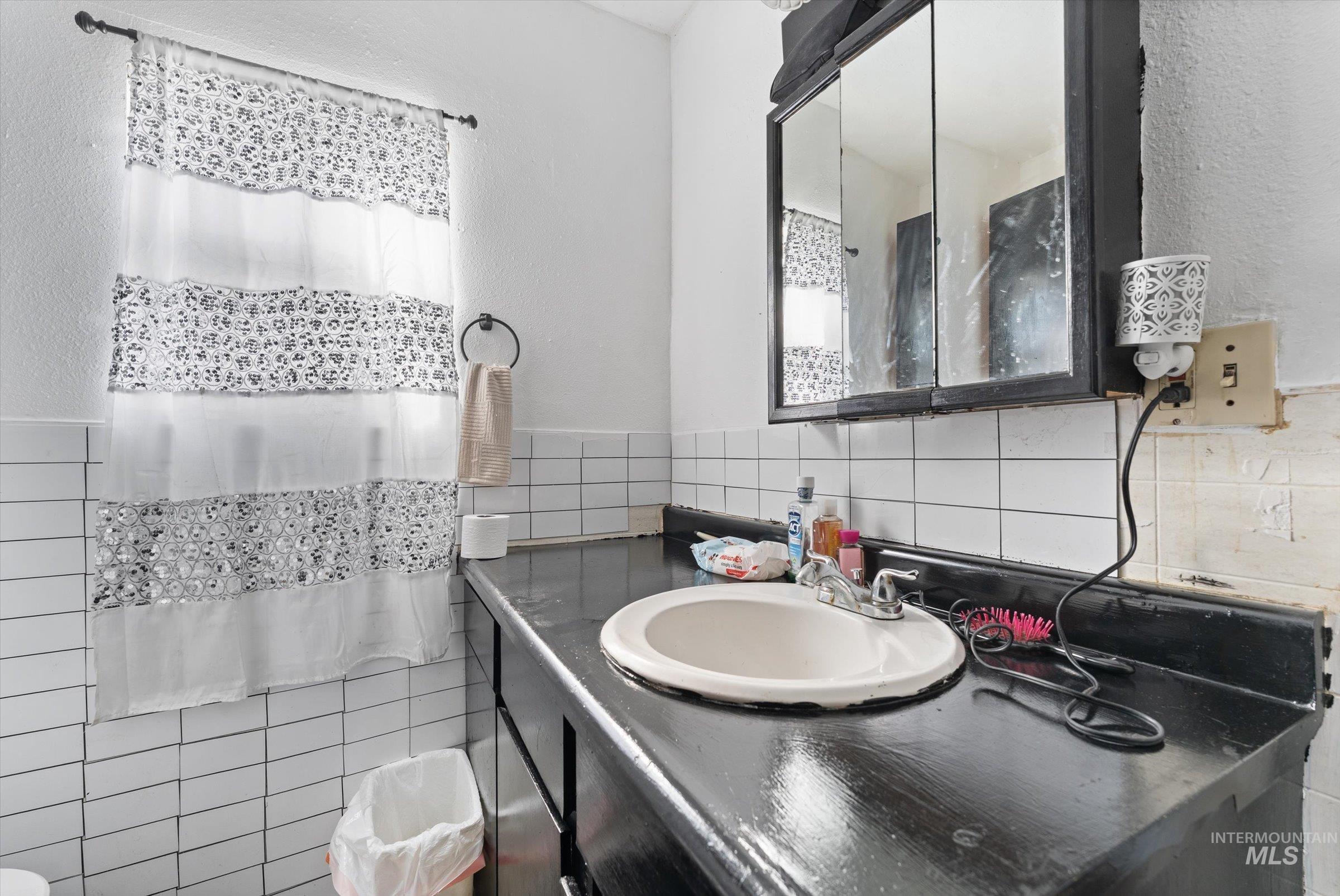 20286 Travis Road Wilder, ID 83676 - Photo 18 of 48 Full bath with vanity, a shower with curtain, tile walls, and a textured wall