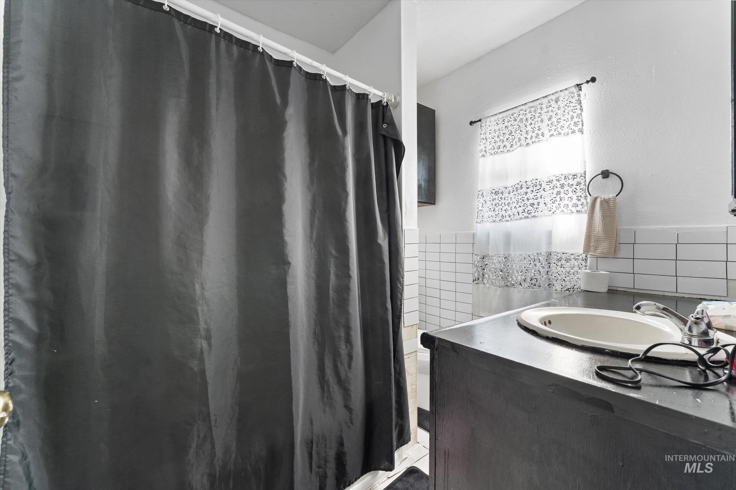 20286 Travis Road Wilder, ID 83676 - Photo 19 of 48 Full bath featuring vanity, a shower with curtain, and tile walls