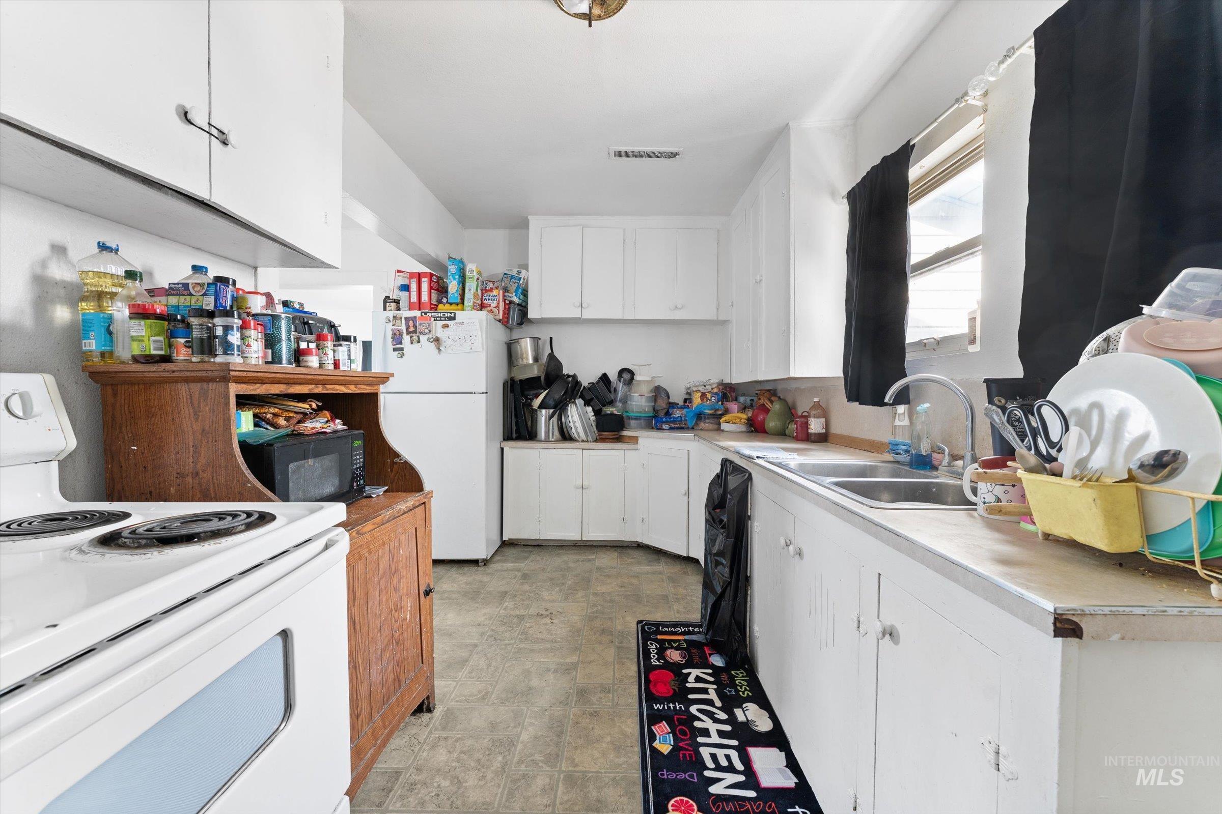 20286 Travis Road Wilder, ID 83676 - Photo 10 of 48 Kitchen featuring white appliances, white cabinetry, and light countertops