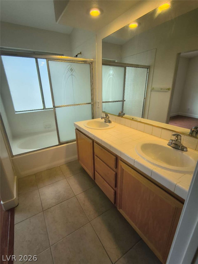 9725 Pima Point Avenue Las Vegas, NV 89147 - Photo 17 of 35 A well-lit primary bathroom features a double vanity and a shower-tub combo.