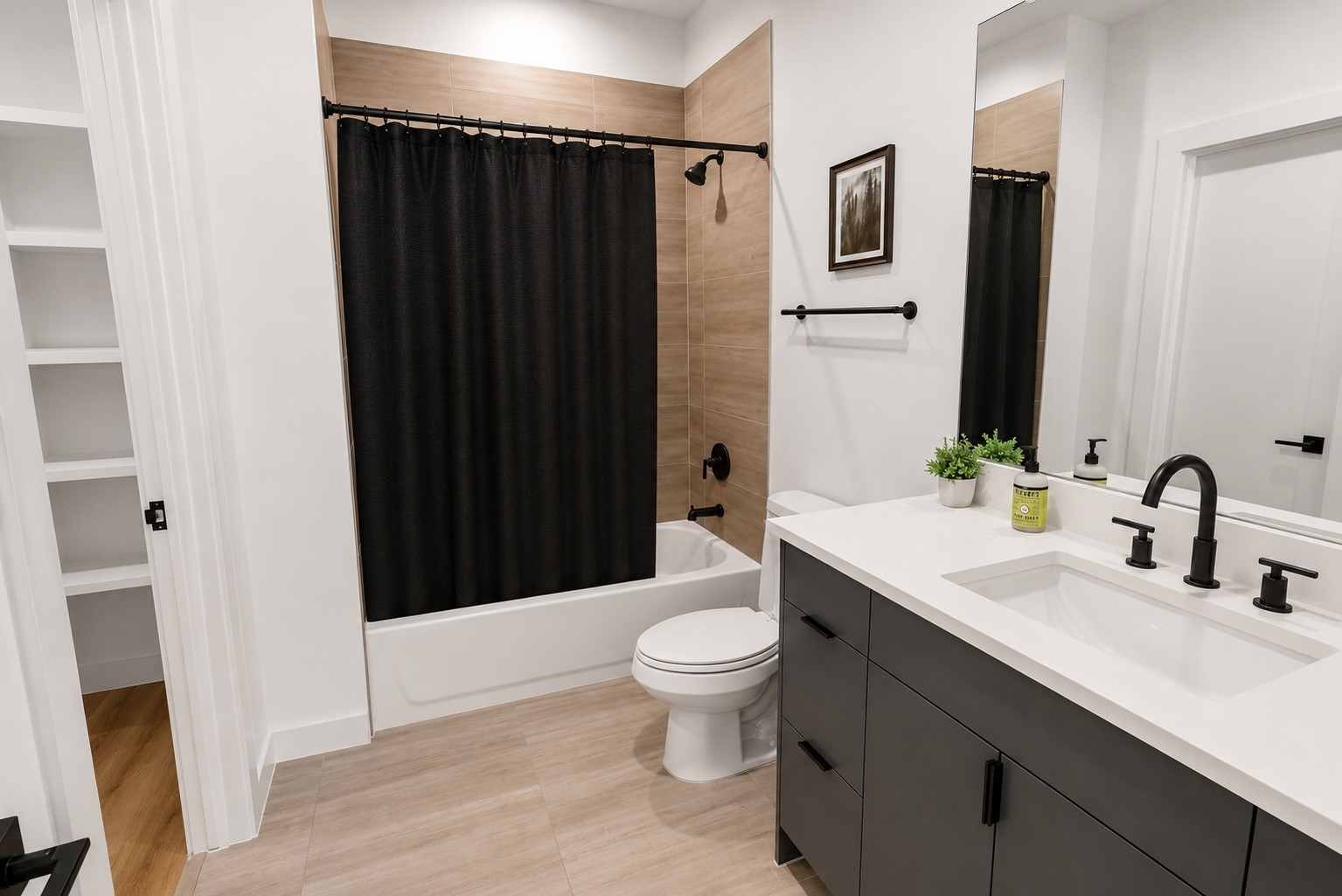 6742 Peerless Street, Unit B Houston, TX 77021 - Photo 21 of 32 Contemporary en suite bath showcases quartz countertops, sleek gray cabinetry, matte black fixtures, and warm porcelain tile surrounding the tub and shower combination. Clean lines and timeless finishes create a polished space designed for both everyday comfort and lasting style.