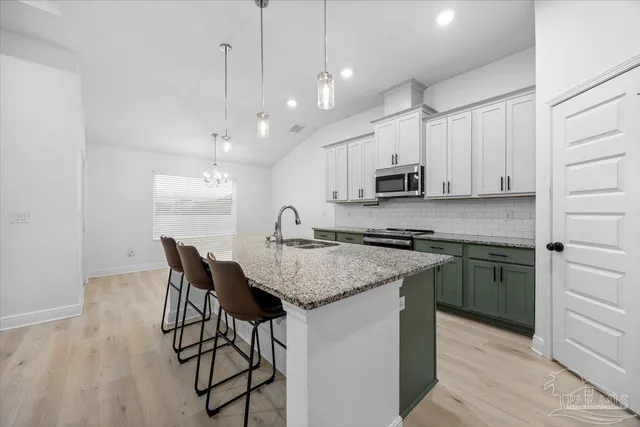 a kitchen with stainless steel appliances granite countertop a stove top oven a refrigerator a sink and a dining table with wooden floor