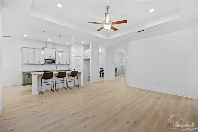 a view of a kitchen with kitchen island a sink stainless steel appliances and a chandelier