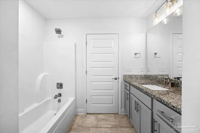 a bathroom with a granite countertop sink a mirror and a bathtub