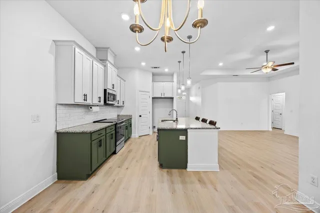 a kitchen with stainless steel appliances granite countertop a sink a stove top oven and cabinetry