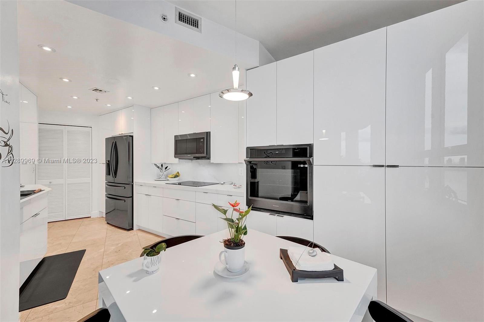 848 Brickell Key Drive, Unit 1602 Miami, FL 33131 - Photo 12 of 33 a kitchen with stainless steel appliances kitchen island granite countertop a sink refrigerator and microwave