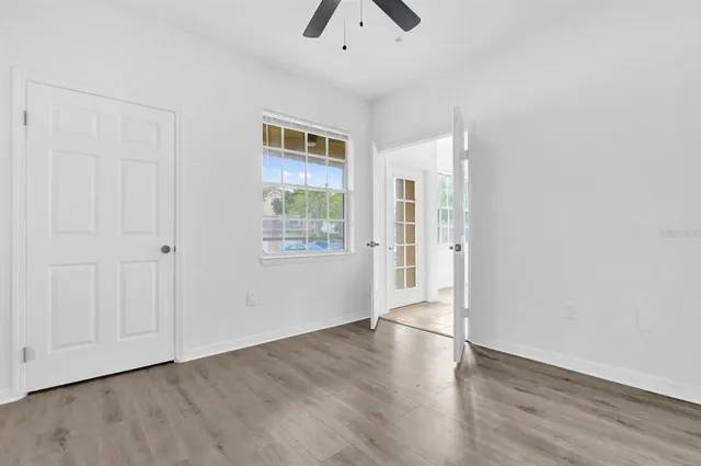 an empty room with wooden floor chandelier and windows