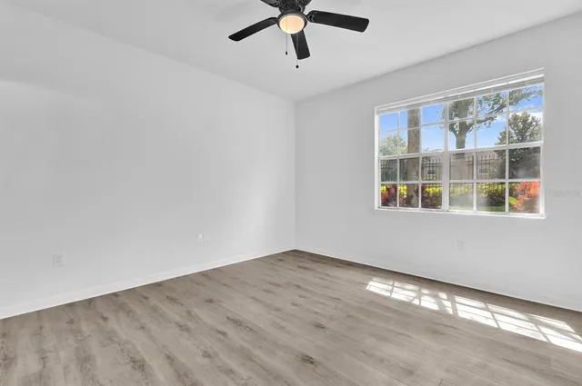 a view of empty room with wooden floor and fan