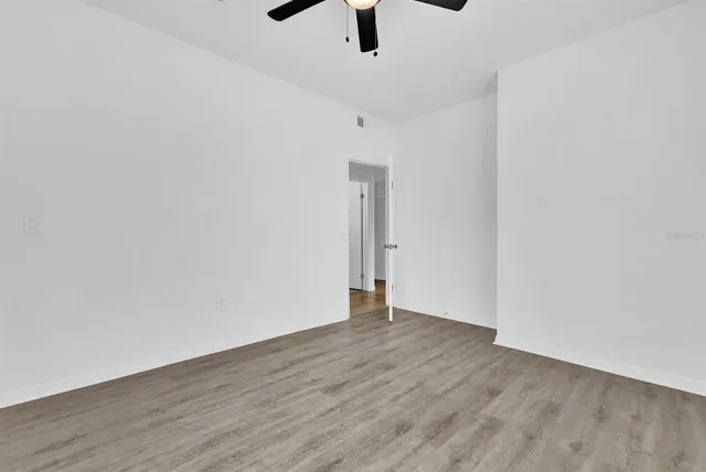 an empty room with a ceiling fan and wooden floor