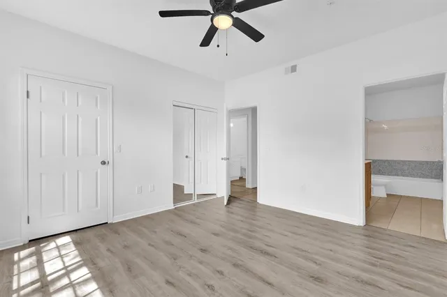 a view of empty room with wooden floor and ceiling fan
