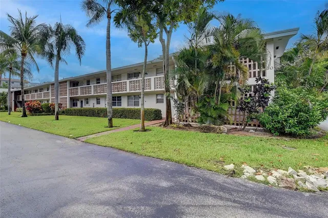 a view of a house with a yard and palm trees
